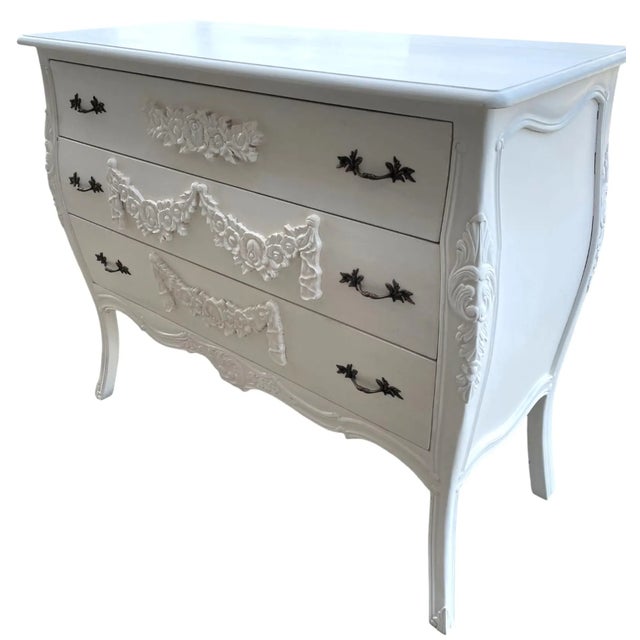 This French Bombay chest features a Louis XIV style with carved floral motifs and a shabby chic white finish, offering a...