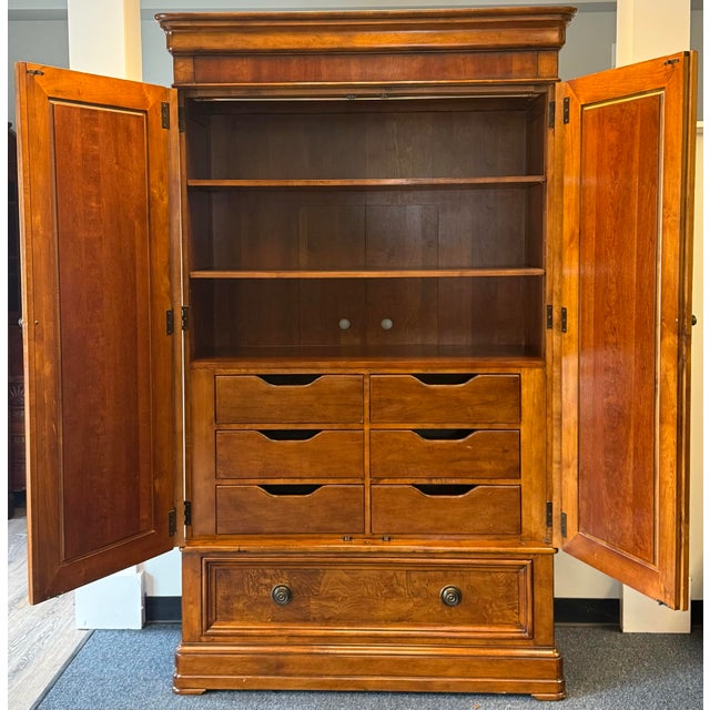 Impressive traditional armoire featuring a warm, rich wood finish and beautifully figured wood-grain panels. The...