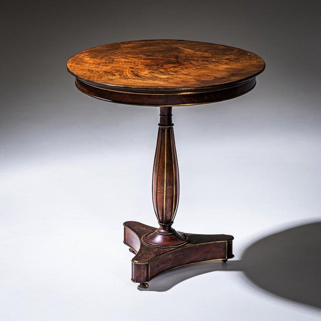 Side table with circular top and trefoil base. The table stands on a baluster-shaped column decorated with brass moldings...