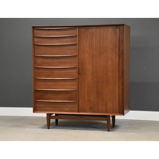 A mid century modern teak armoire dresser with seventeen dovetail drawers and sliding tambour door by Falster....