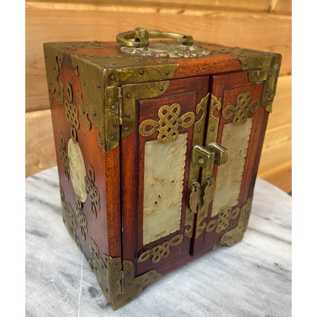 A beautiful mid-century jewelry cabinet with carved jade inset panels and brass hardware. This piece has a lovely feeling...