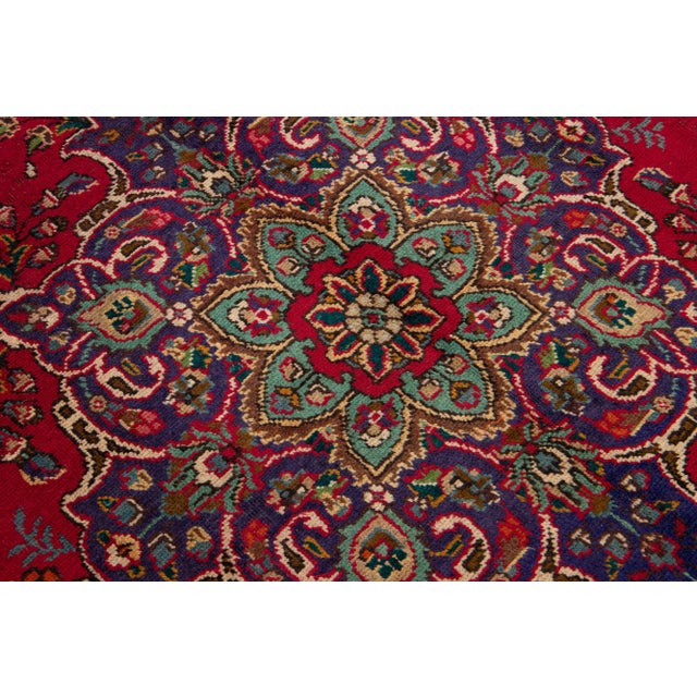 Beautiful vintage Persian Tabriz hand-knotted wool rug with a red color field. This piece has a navy blue frame and...
