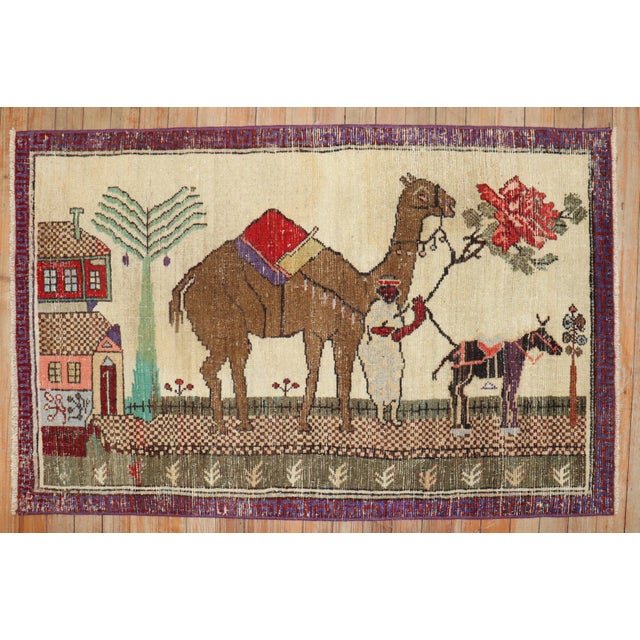 Mid-20th century colorful worn Turkish rug depicting camel and donkeys on an ivory ground. Size: 2'5'' x 3'11''.
