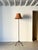 A vintage metal floor lamp of simple unadorned design, overpainted in brown. This iron standard light has a sturdy tripod...