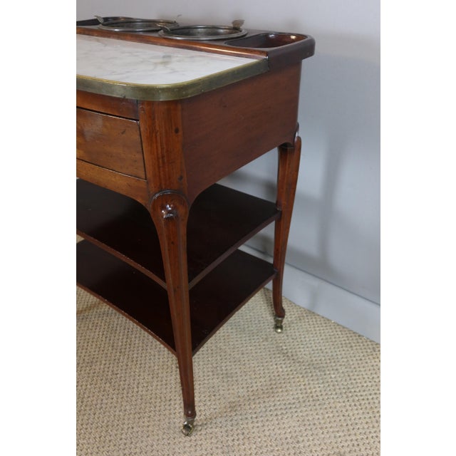 Walnut refreshment table resting on four curved legs connected by two Transition-style shelves. It opens with a drawer...