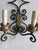 Elegant pair of handcrafted wrought iron wall sconces featuring graceful scrollwork and decorative gilt acanthus leaf...