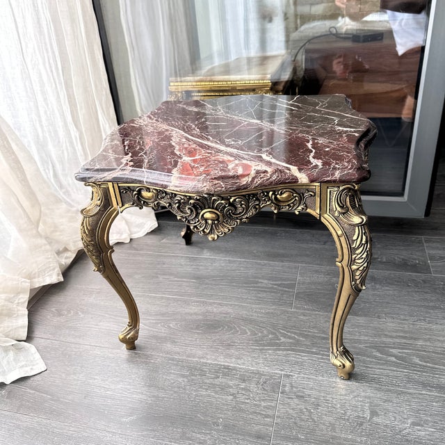 An exceptional vintage Italian side table with a striking burgundy marble top and an intricately relief-decorated brass...