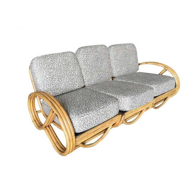 This beautifully restored Post War three strand, 3/4 round pretzel arm rattan section sofa for 3 people, features a rare...