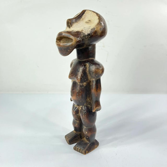 This finely carved wooden figure with Kaolin (clay) painted on its face originates from the Zimba people of the Democratic...