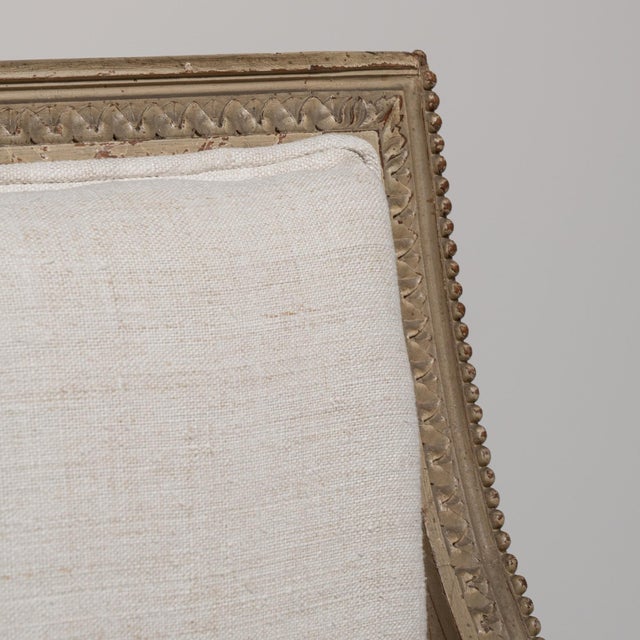 A cream wood, Louis XVI-style armchair, dating to the 19th century and made in France. The wood frame is finished in...