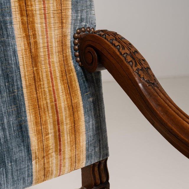 This piece presents as a armchair, distinguished by dark wood frame, blue/gold striped upholstery. It was made in France...