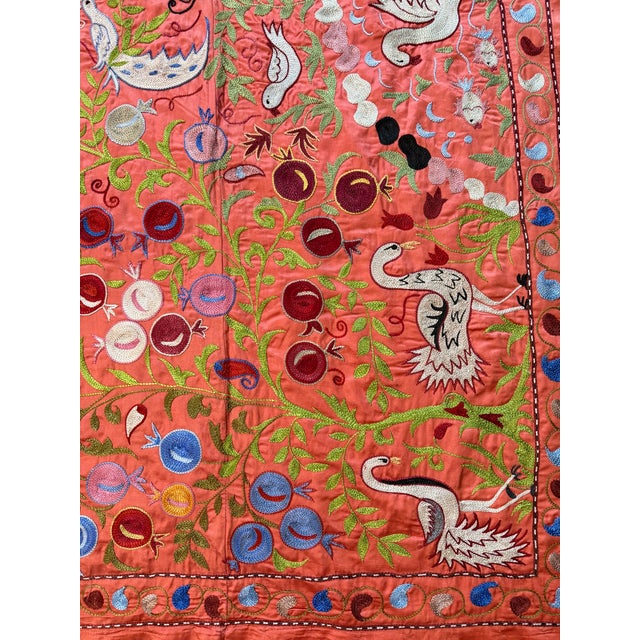 Hand-embroidered Suzani panel from Uzbekistan — white cranes and birds among dotted rosettes and green vines on a coral...