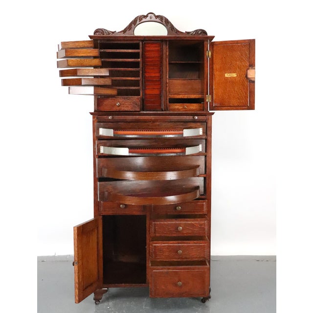 1890s Victorian style dental cabinet made of dark stained quarter sawn oak on casters. It was made by Ransom & Randolph...