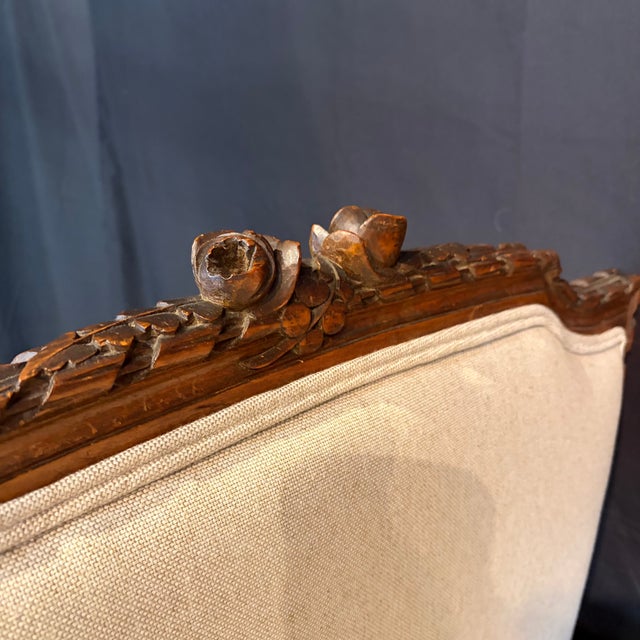 Elegant antique French Louis XVI carved walnut daybed and settee featuring a beautifully detailed neoclassical frame and...
