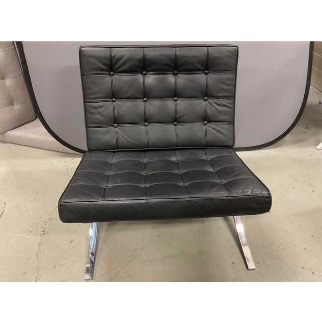 Barcelona-style chairs featuring tufted black upholstery with button details on backrests and seats. X-shaped chrome...
