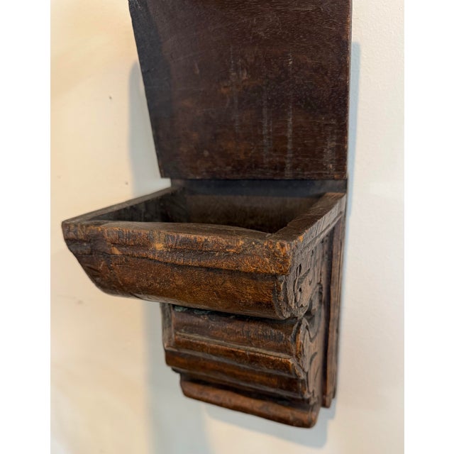 A wonderfully unusual antique French carved wood corbel featuring a richly aged dark finish, hand-carved scrollwork, and a...