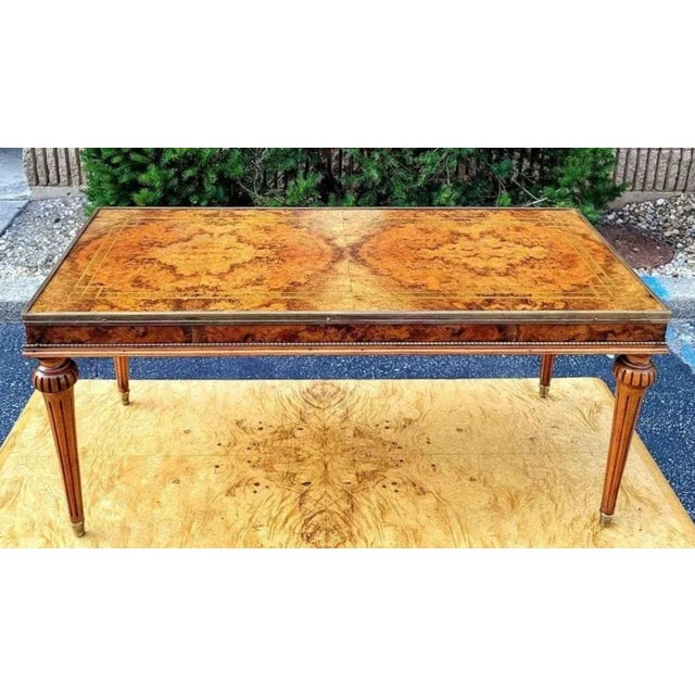 Featured is a lovely Hollywood Regency Bookmatched Burl Top Coffee Table. Bulbous topped fluted legs terminate in brass...