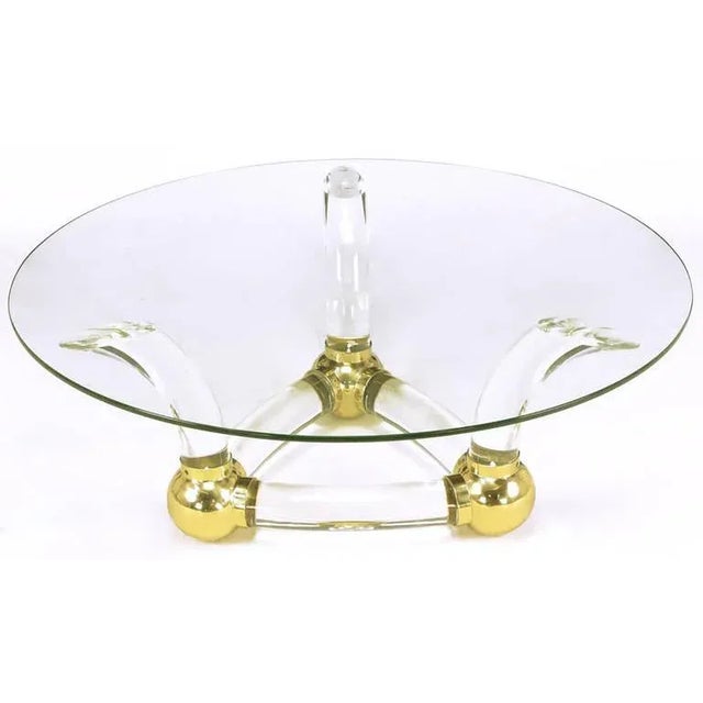Thick curved bar Lucite and brass ball fitments coffee table. Triangular base with three horn-shaped supports. 1/2" thick...