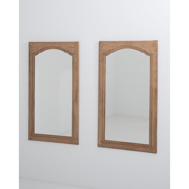 A pair of 19th century French wall mirrors in oak presented in a taller vertical format. The elongated proportions...