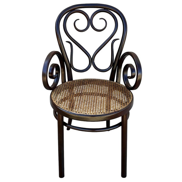 The Victorian Thonet number 04 armchair features an elegant, sculptural frame crafted from warm-toned bentwood with...