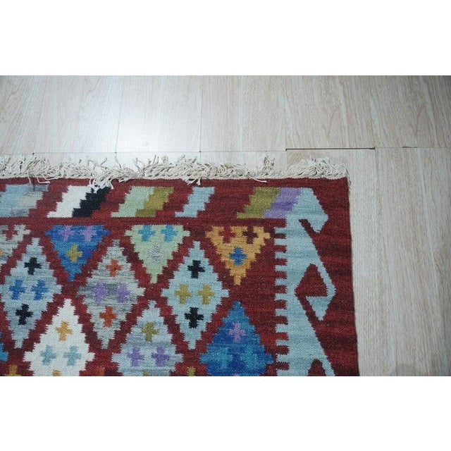 This multicolor jewel tone rug is a flat weave kilim crafted from durable wool. The textile features a sturdy construction...