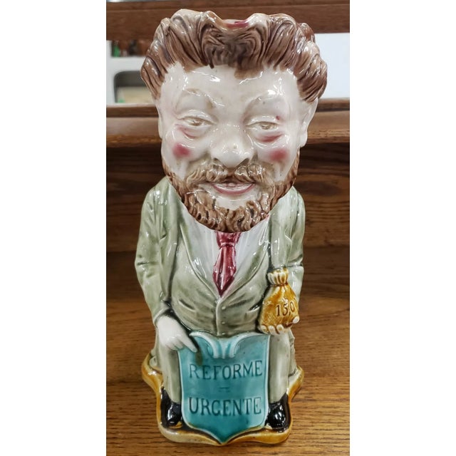 This is an Early 20th Century French Onnaing Majolica Camille Pelletan Figural Pitcher. It measures 11" tall, 5" wide and...