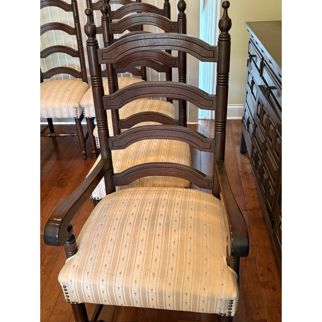 Eight oak matching chairs: 2 end chairs with arms and 6 side chairs, each upholstered in light yellow stripes, and...