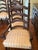 Eight oak matching chairs: 2 end chairs with arms and 6 side chairs, each upholstered in light yellow stripes, and...