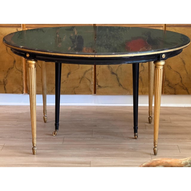 This Maison Jansen dining table features a round black lacquered top with a molded edge sitting over a frieze trimmed in a...