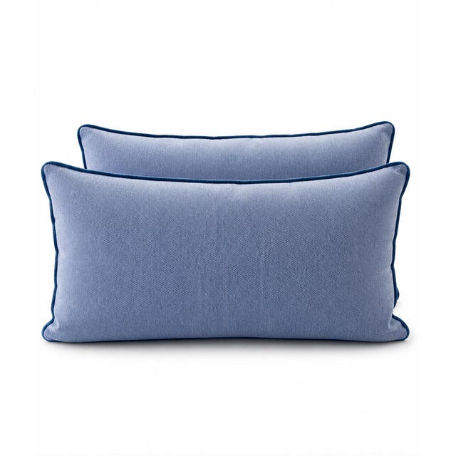 A chic pair of blue and white lumbar pillows featuring a delicate bird and botanical motif, rendered in a soft, painterly...