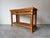 A stylish vintage coastal rattan console table featuring a two-tier design with woven cane panels and subtle leather-...