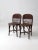 A pair of antique wicker chairs distinguished by their low backs, rounded seats, and distinctive thatched detailing. The...