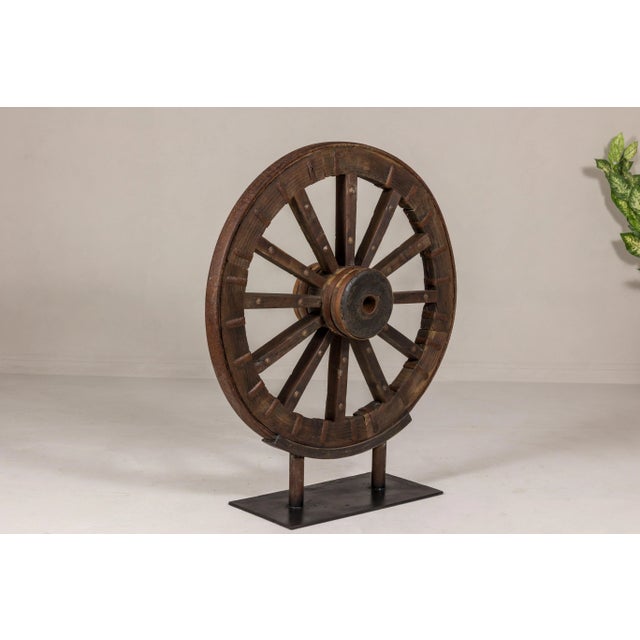 An antique Indian wood and metal cart wheel mounted on custom black metal base. Introduce a touch of rustic authenticity...