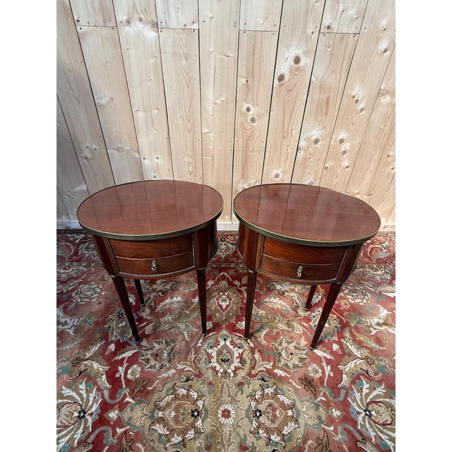 An elegant pair of Louis XVI style bedside tables dating from the 19th century. Each table features a refined oval shape...