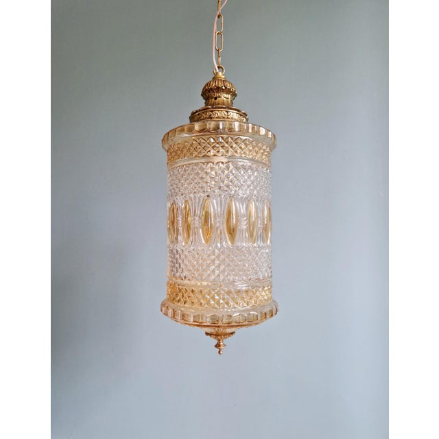 Large lantern-type pendant light, in transparent and orange glass, fitted with a brass frame, 1960s. The suspension has...
