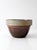 This antique American stoneware mixing bowl features a classic utilitarian form with a soft buff-gray rim and rich brown...