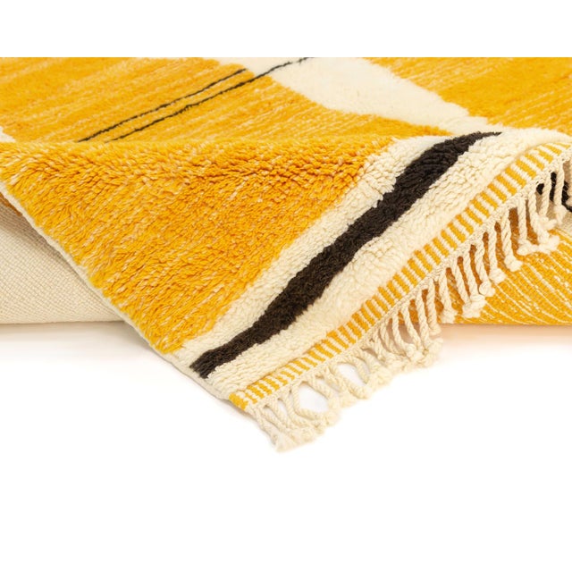 Vibrant hand-knotted wool rug showcases abstract silhouettes in Navy Blue and Saffron against an Ivory backdrop, creating...