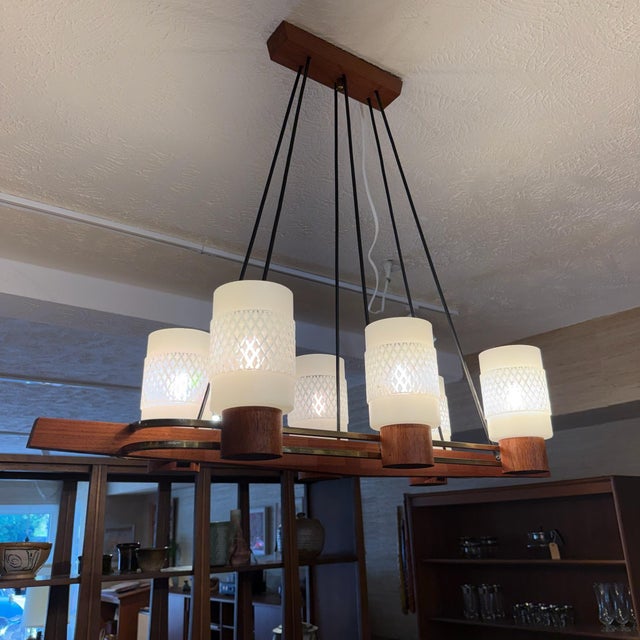 A striking Danish modern chandelier crafted from warm teak with sculptural brass accents and six textured glass shades....