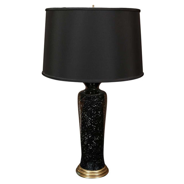 A striking pair of tall table lamps featuring a sleek, columnar silhouette finished in a dramatic black crackle glaze. The...