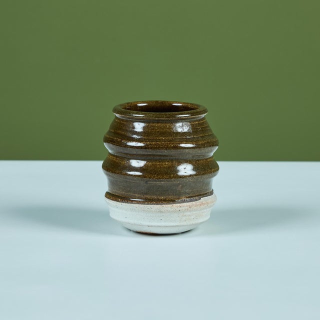 Small studio pottery cup with a ribbed body and two-tone glaze. The upper half and interior is glazed in a glossy olive...