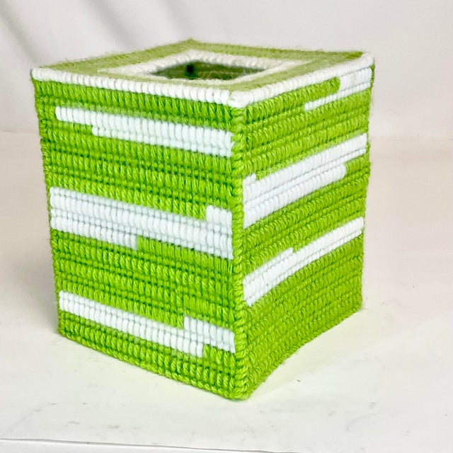 This Tissue Box Cover is a folk art piece from the 1970s. The artist woven lime green and white yarn into a plastic grid...