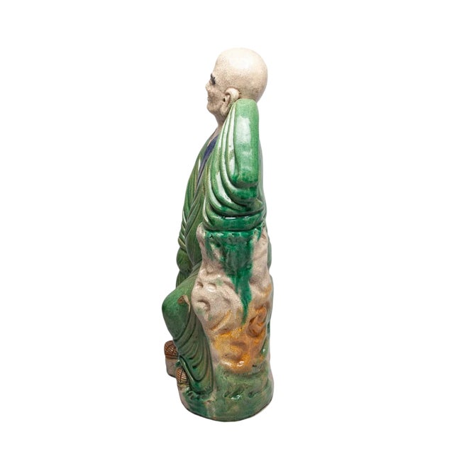 This large antique Chinese Shiwan pottery figure depicts a serene Luohan (Arhat) in a contemplative pose, leaning against...