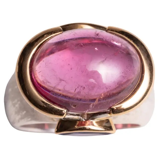 A spectacular large pink tourmaline cabochon dome ring set in 18K gold. It is flanked by two marquise cut tanzanite stones...