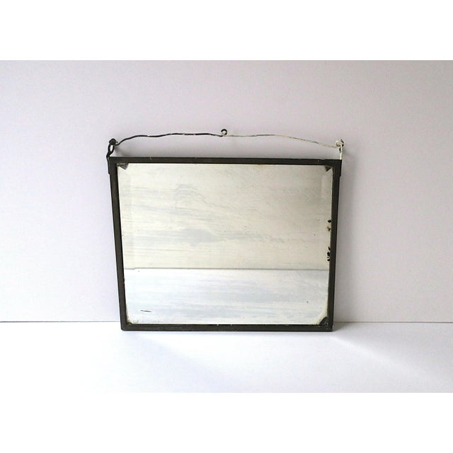 An antique wall mirror shaving vanity mirror, circa early-20th century. Mirror is rectangular, beveled, embraced by metal...