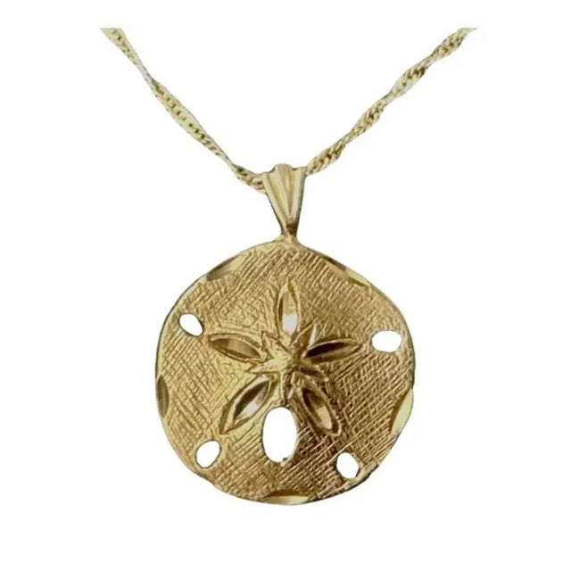 14K Gold Sand Dollar Pendant. Pendant features finely detailed textured surface and cutout accents that capture the...