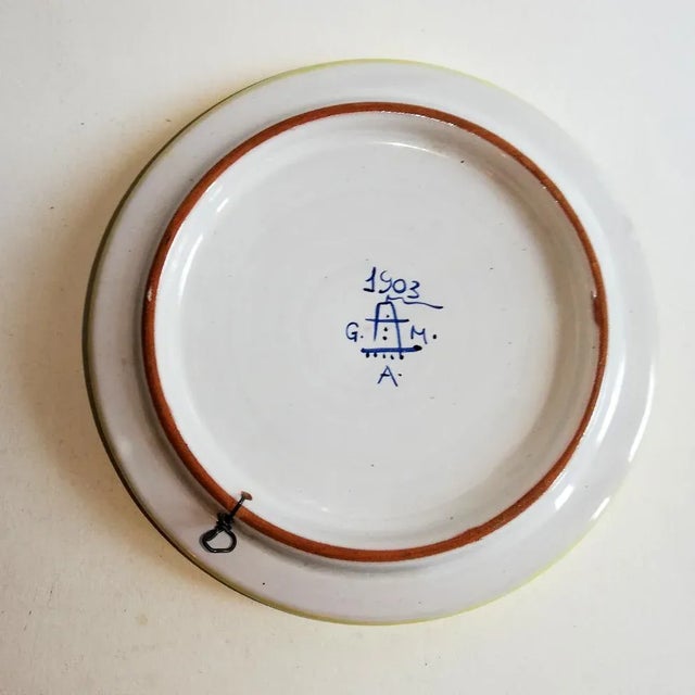 This ceramic centerpiece is decorated with plants. It dates from 1903 and is signed 'GAMA'.