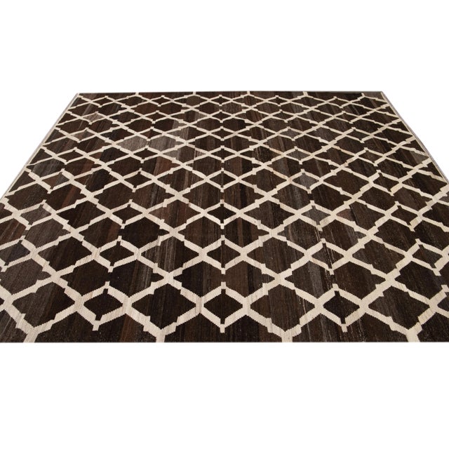 Beautiful hand knotted flat-weave kilim wool rug. This rug has a dark brown field with ivory accents in an all-over...