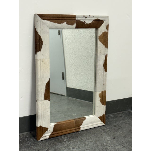 Design Plus Gallery presents the Charles Mirror from Made Goods. This rectangular mirror has a brown and white hair-on-...