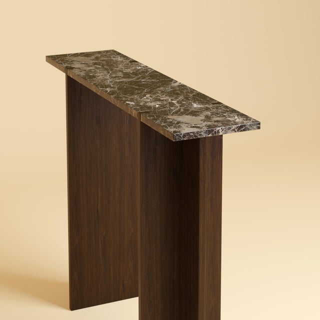The Maha is an Emperador Dark marble and oak console table, a slim, upright table made to sit against a wall. Stone and...