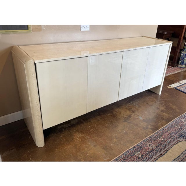 This modern buffet features a striking polished marble top and stone sides, offering a bold and architectural presence....